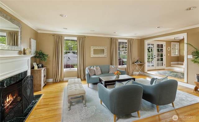 living room featuring a premium fireplace, baseboards, ornamental molding, and light wood finished floors
