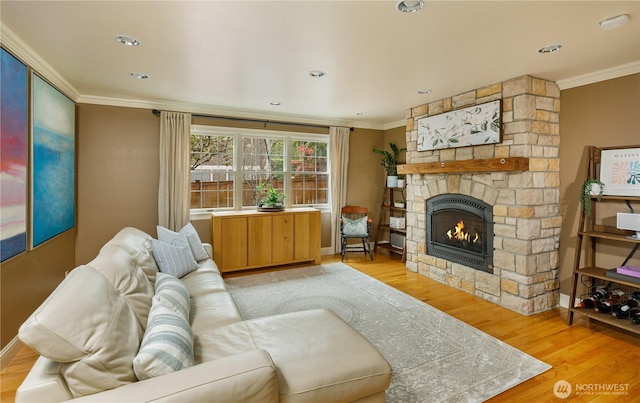 living room with crown molding, light wood-style floors, baseboards, and a stone fireplace