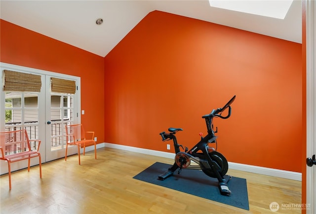 exercise area with french doors, baseboards, wood finished floors, and vaulted ceiling with skylight