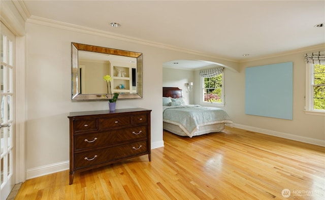 bedroom featuring baseboards, multiple windows, ornamental molding, and light wood-style floors