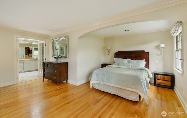 bedroom featuring crown molding, arched walkways, baseboards, and light wood-style flooring