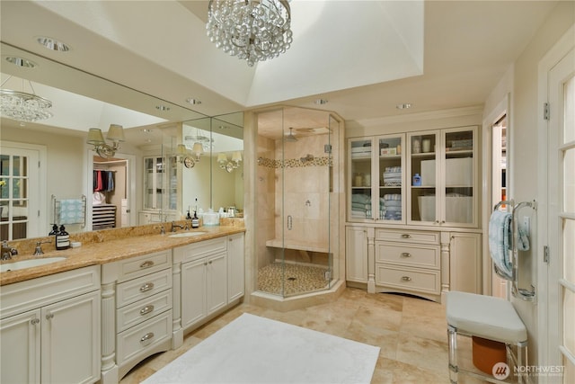 bathroom featuring a sink, an inviting chandelier, a shower stall, and double vanity