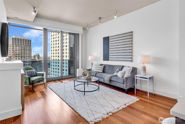 737 Olive Way Unit 3101, Seattle, WA 98101 - living room featuring rail lighting, wood finished floors, a city view, and baseboards