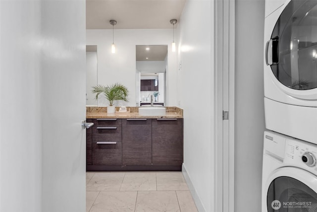 737 Olive Way Unit 3101, Seattle, WA 98101 - washroom featuring stacked washer and clothes dryer, light marble finish floors, and baseboards