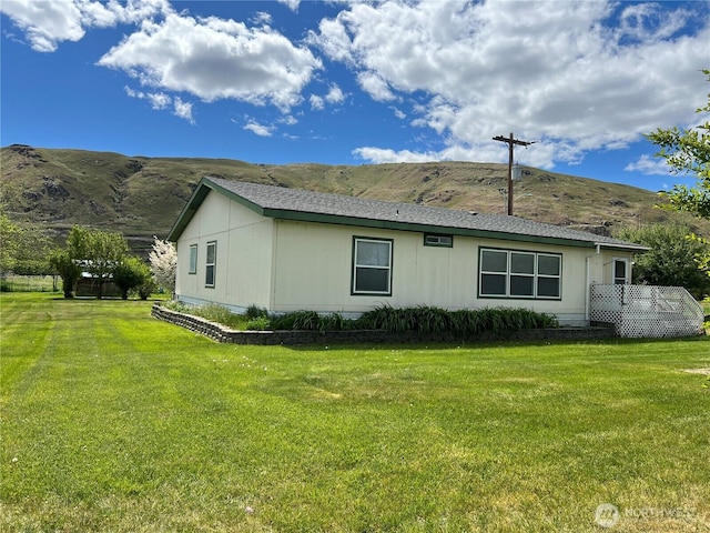 view of side of property with a lawn and a mountain view