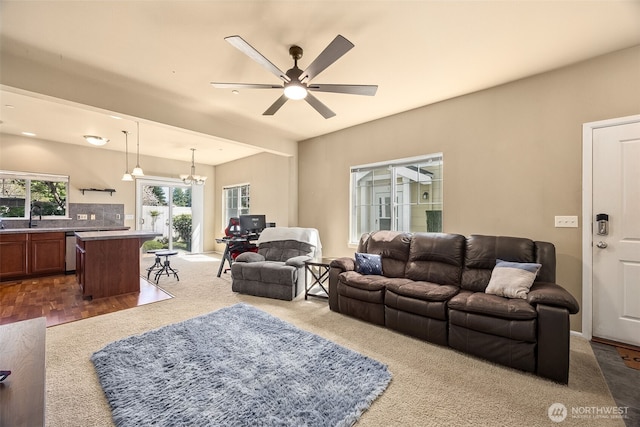 living area featuring dark carpet and ceiling fan with notable chandelier