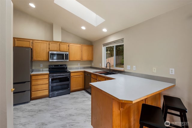 kitchen featuring a sink, marble finish floor, stainless steel appliances, a peninsula, and lofted ceiling with skylight