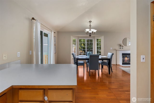 dining room with a fireplace, vaulted ceiling, wood finished floors, and a chandelier