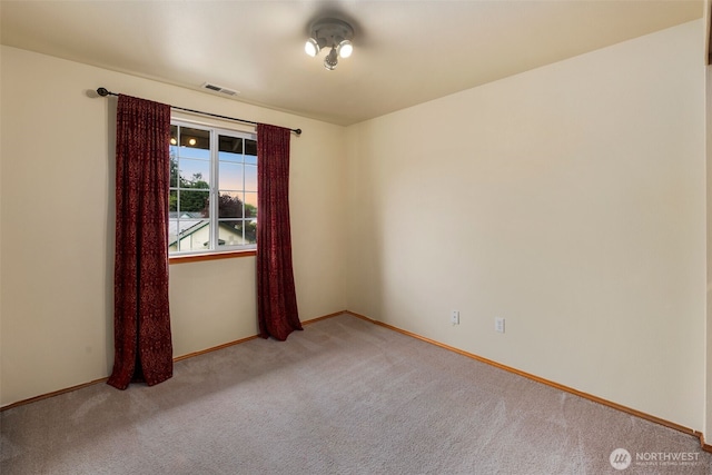 spare room featuring visible vents, baseboards, and light carpet