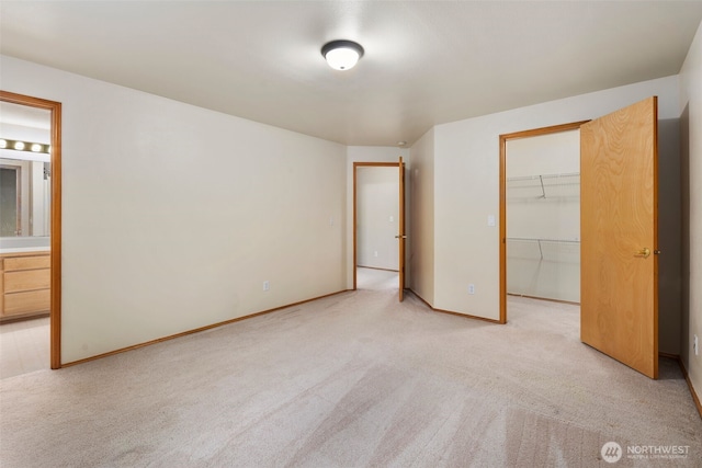 unfurnished bedroom featuring a walk in closet, light carpet, a closet, and connected bathroom