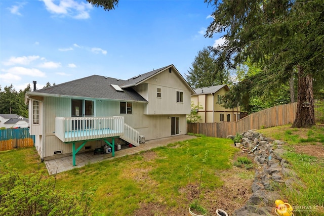 back of property with roof with shingles, a deck, a fenced backyard, a yard, and a patio