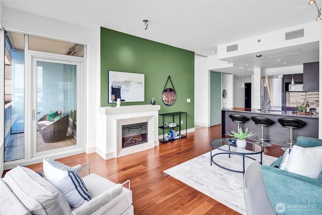 living room with wood finished floors, a fireplace, baseboards, and stacked washing machine and dryer