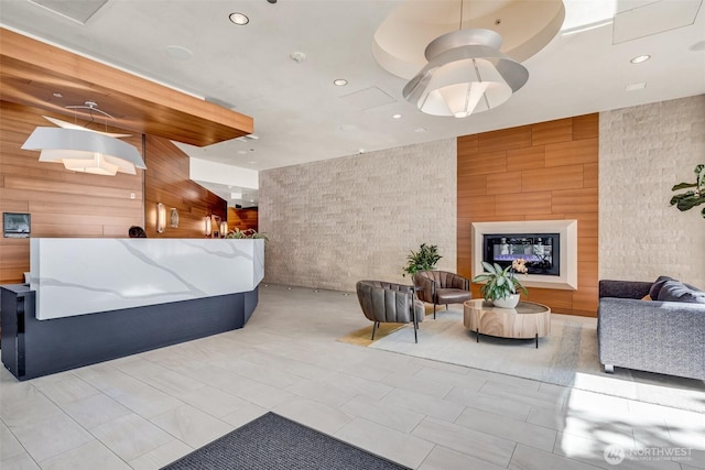 reception area featuring wood walls, recessed lighting, and a glass covered fireplace