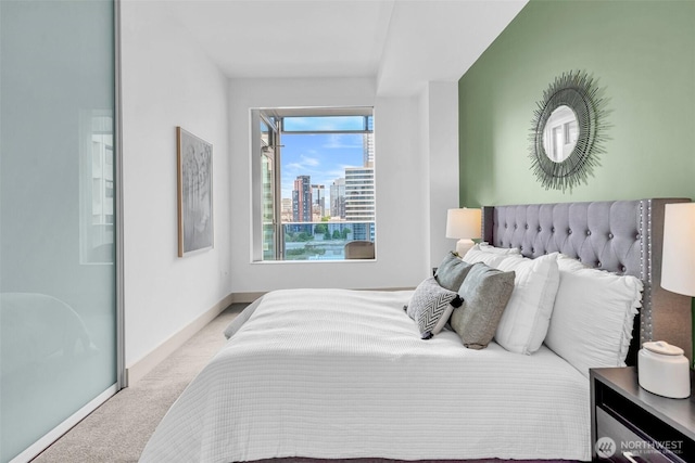 carpeted bedroom featuring baseboards and a city view
