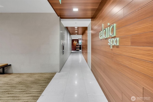 corridor featuring wooden walls, wood ceiling, and tile patterned flooring