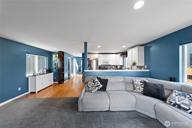 living area featuring light colored carpet, baseboards, light wood-type flooring, and recessed lighting