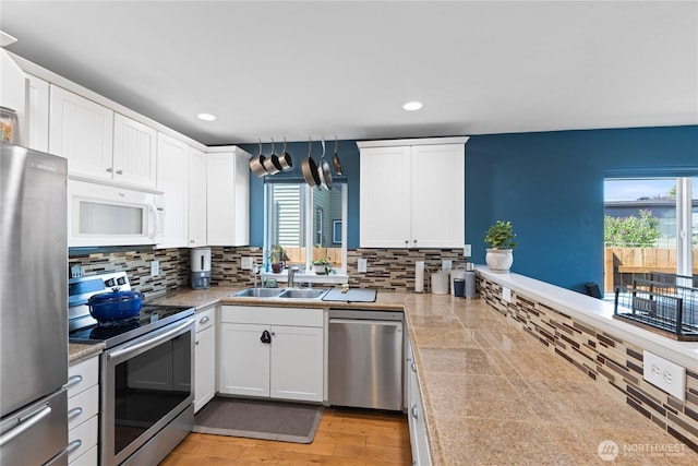 kitchen featuring stainless steel appliances, a sink, white cabinetry, and tasteful backsplash