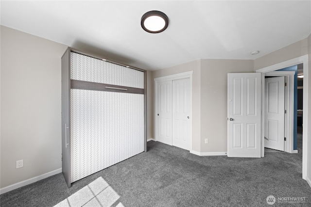 unfurnished bedroom featuring baseboards, dark carpet, and a closet