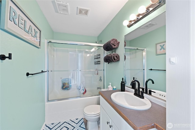 bathroom with toilet, vanity, bath / shower combo with glass door, and visible vents