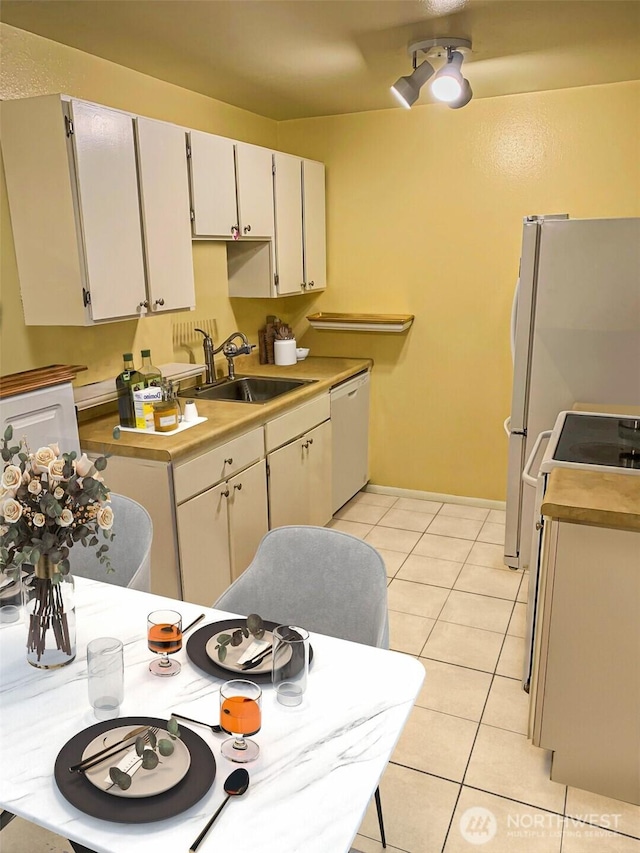 6110 24th Ave NW Unit 203, Seattle, WA 98107 - kitchen with white dishwasher, a sink, electric stove, light tile patterned floors, and light countertops