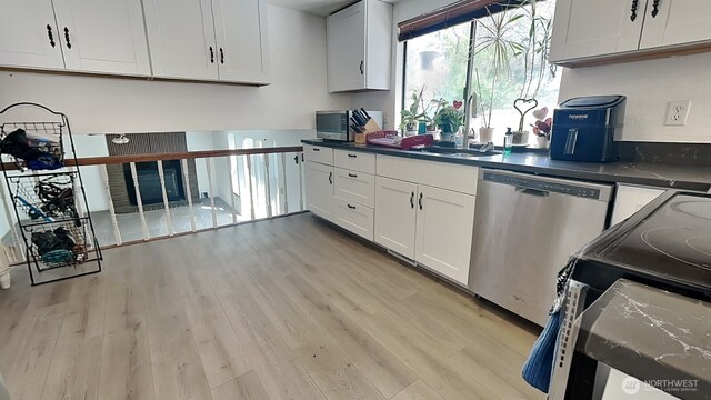 kitchen with dark countertops, light wood-style floors, stainless steel dishwasher, and a sink