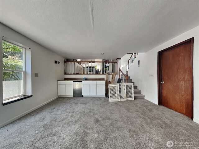 kitchen with fridge, light carpet, dark countertops, white cabinetry, and a textured ceiling