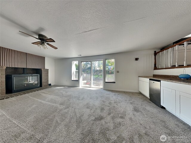 unfurnished living room featuring a fireplace, a textured ceiling, a ceiling fan, and baseboards