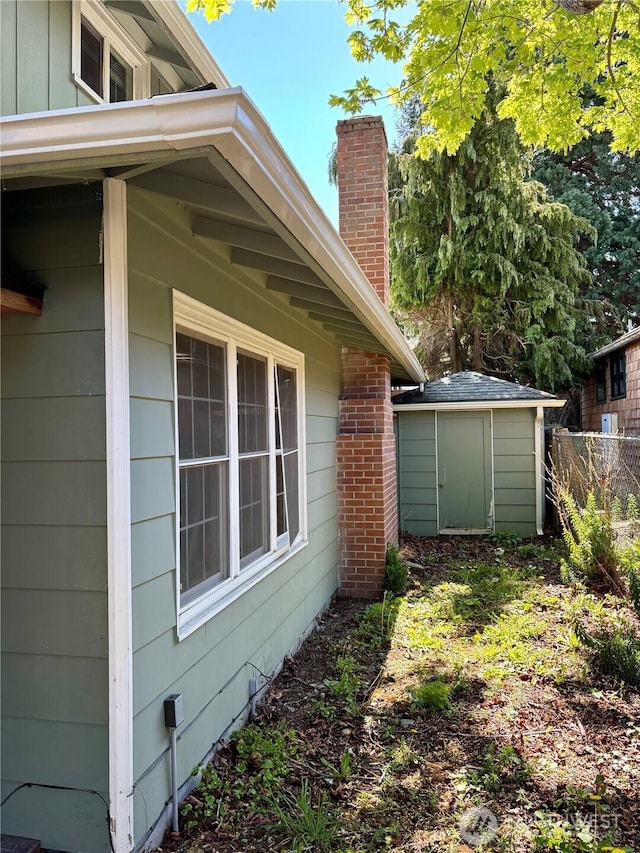 1145 Blaine St, Port Townsend, WA 98368 - view of home's exterior featuring a storage unit, an outbuilding, a chimney, and fence