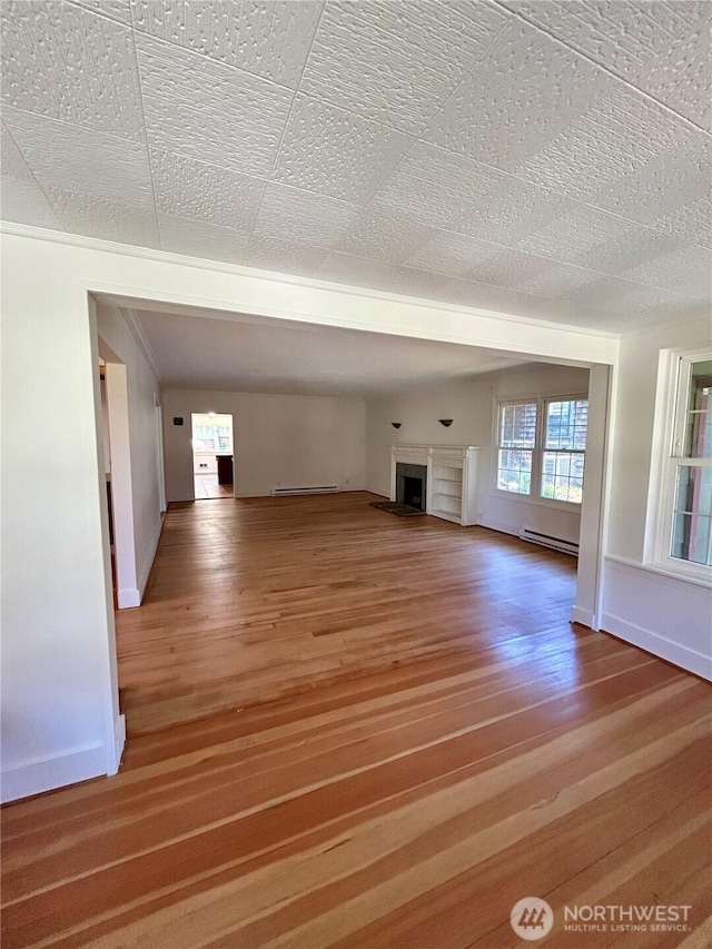 1145 Blaine St, Port Townsend, WA 98368 - unfurnished living room featuring a baseboard heating unit, baseboards, wood finished floors, and a fireplace