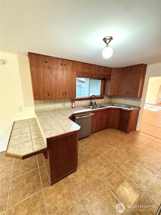 1145 Blaine St, Port Townsend, WA 98368 - kitchen with stainless steel dishwasher, tasteful backsplash, a sink, brown cabinetry, and a peninsula