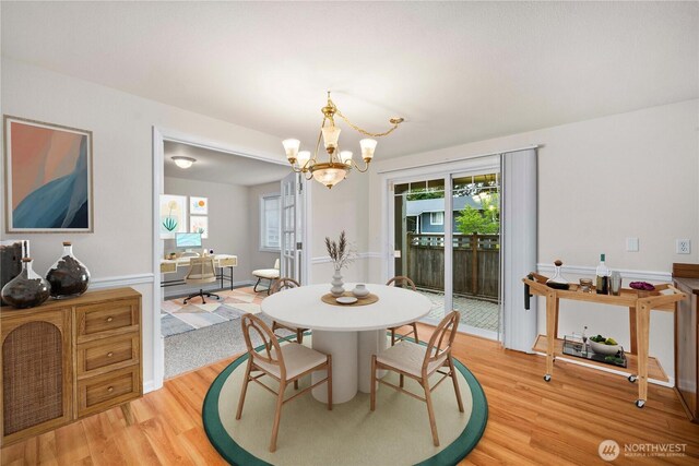 dining space with light wood-type flooring and a chandelier