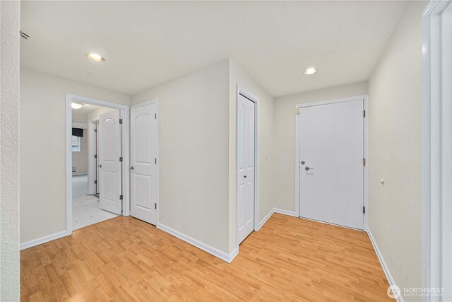 hall featuring light wood-type flooring, recessed lighting, and baseboards