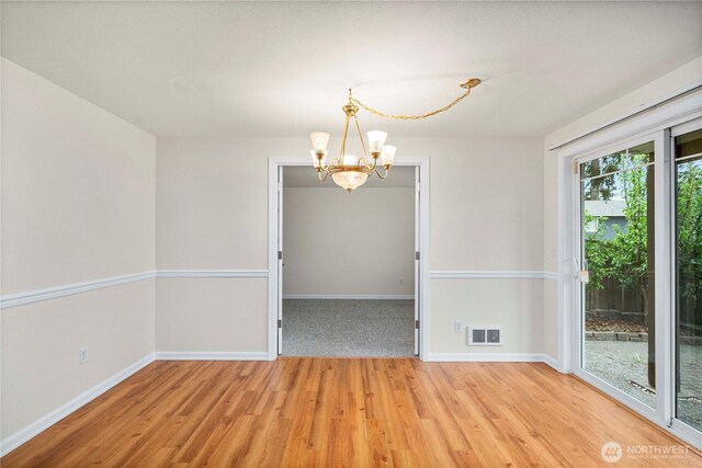 unfurnished dining area featuring visible vents, light wood-style floors, baseboards, and a notable chandelier