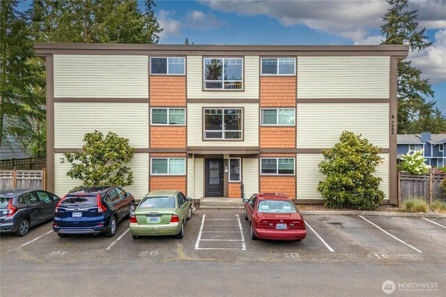 view of building exterior featuring fence and uncovered parking