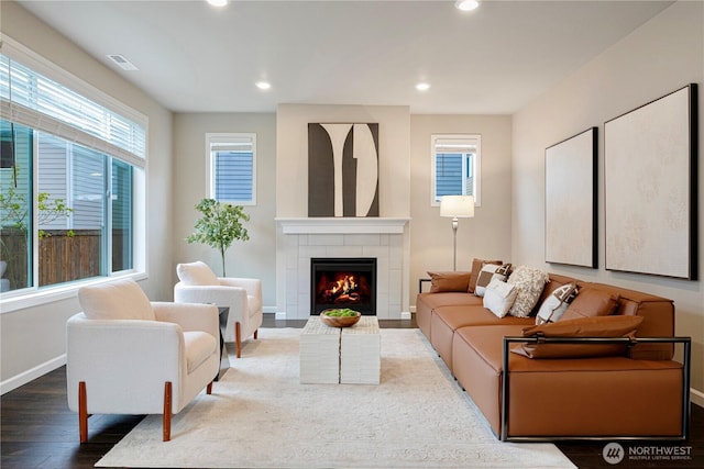 living room featuring a tiled fireplace, recessed lighting, baseboards, and wood finished floors