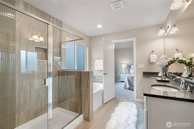 ensuite bathroom featuring connected bathroom, a sink, a shower stall, visible vents, and a bath