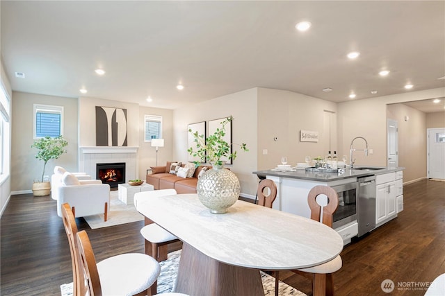 dining space featuring visible vents, baseboards, a lit fireplace, recessed lighting, and dark wood finished floors