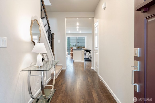 hallway with stairway, baseboards, and dark wood-type flooring