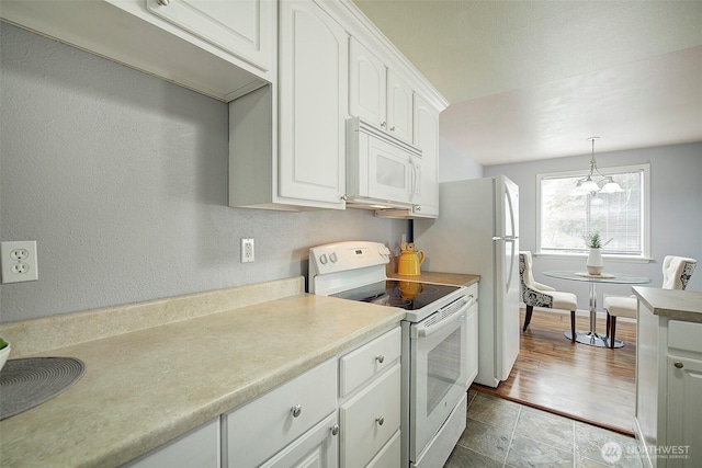 kitchen featuring white cabinets, white appliances, light countertops, a chandelier, and pendant lighting