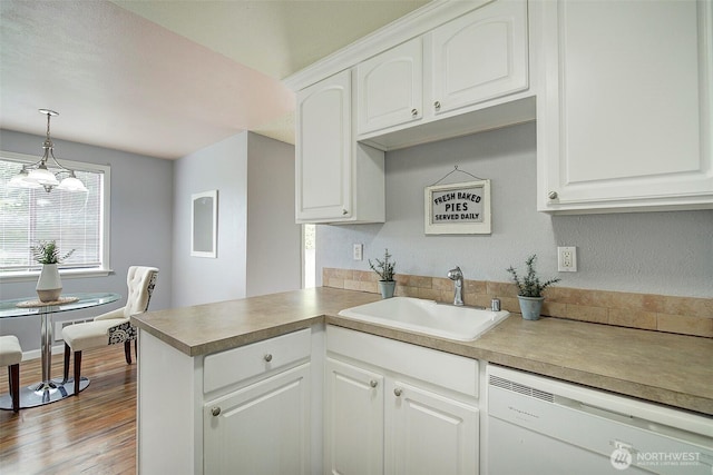 kitchen with white cabinets, a sink, dishwasher, a peninsula, and pendant lighting