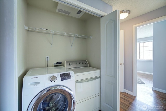 laundry area featuring laundry area, baseboards, wood finished floors, visible vents, and washing machine and dryer