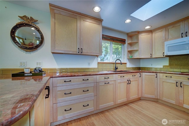 kitchen featuring a sink, white microwave, recessed lighting, a skylight, and light brown cabinets