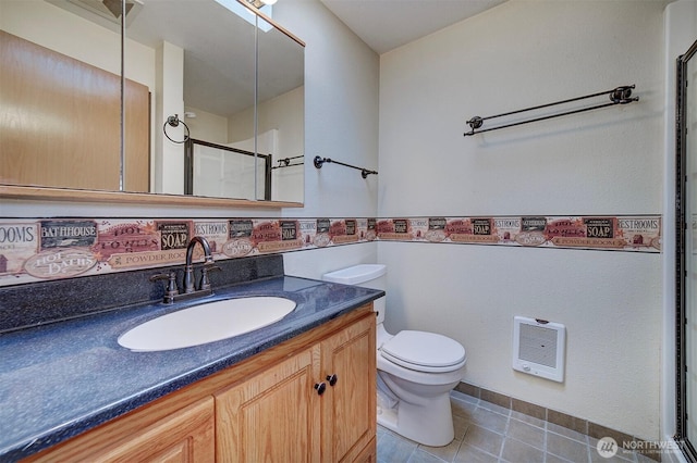 full bath with heating unit, vanity, a shower with shower door, toilet, and tile patterned flooring