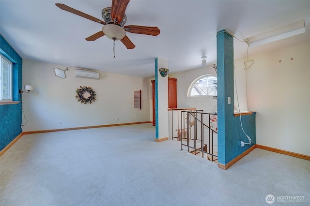 unfurnished room featuring a wall mounted AC, carpet floors, a ceiling fan, and baseboards