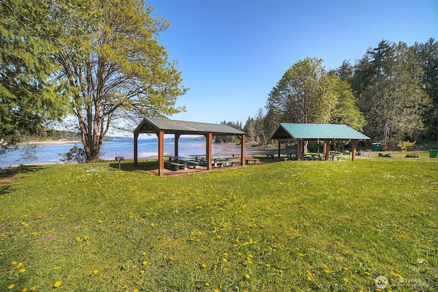 view of dock with a gazebo, a yard, and a water view