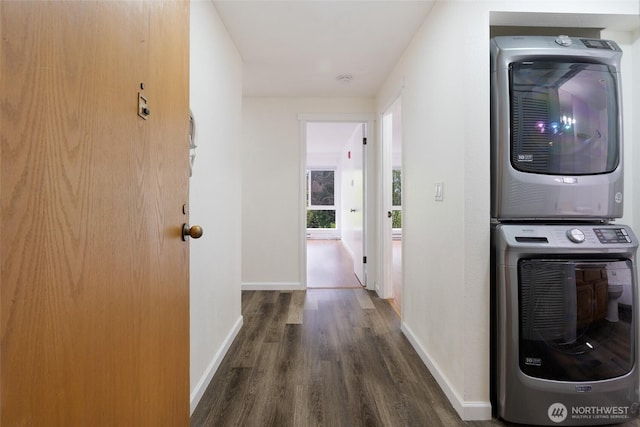 hall with baseboards, stacked washer / drying machine, and wood finished floors