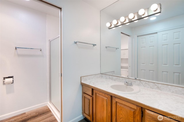 full bathroom featuring vanity, baseboards, a stall shower, and wood finished floors