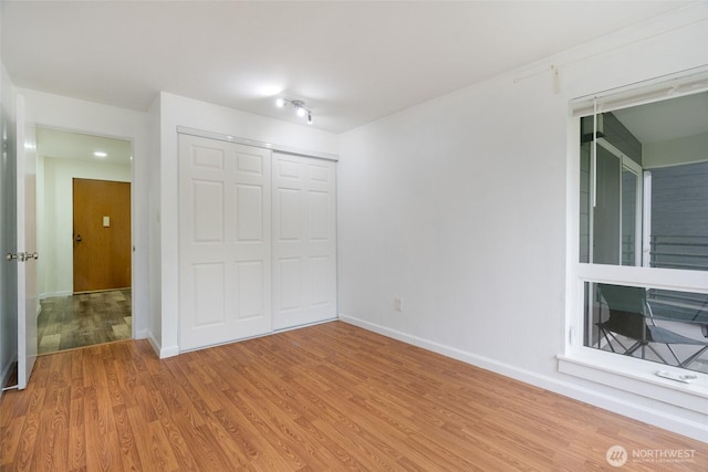 unfurnished bedroom with light wood-style floors, baseboards, and a closet