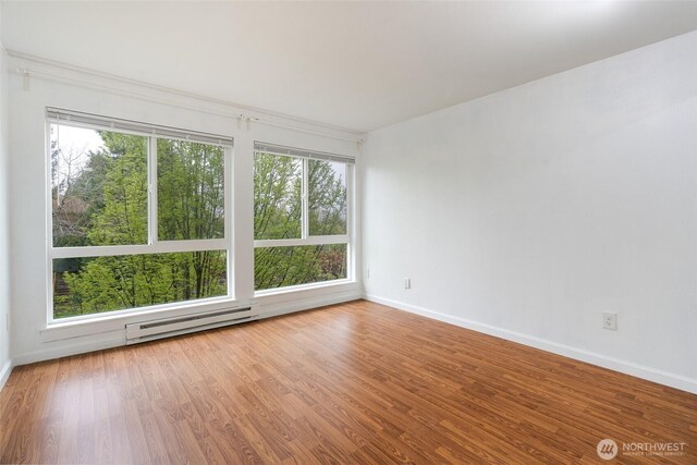 spare room featuring baseboards, a baseboard radiator, and plenty of natural light