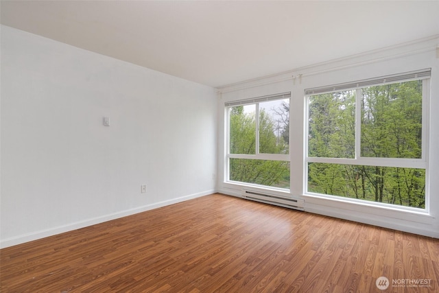 unfurnished room with baseboards, plenty of natural light, wood finished floors, and a baseboard radiator